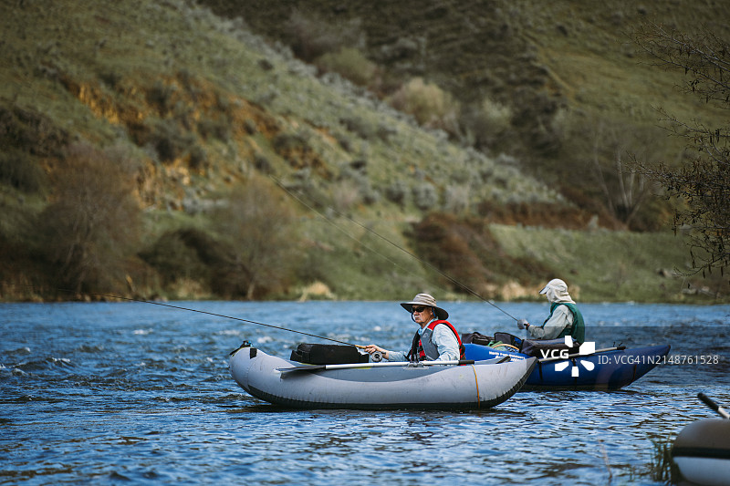 两个成熟的男人坐在充气船上钓鱼图片素材