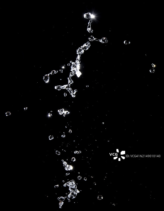 黑色背景上向上运动的水花和水滴。图片素材