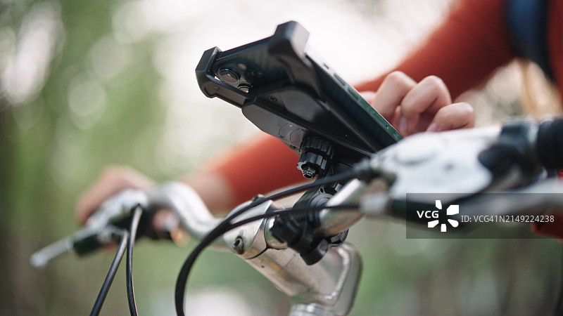 女子骑自行车旅行时使用智能手机。图片素材