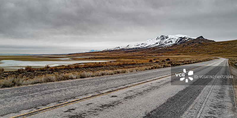 空旷的道路通往白雪皑皑的山脉对天空，博纳维尔盐平原，犹他州，美国，美国图片素材