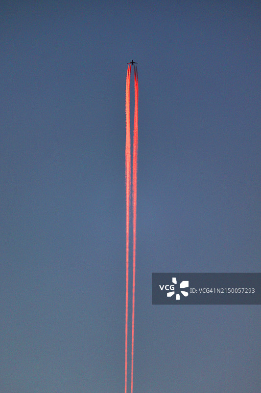 蓝色天空中喷气式飞机的粉红色轨迹图片素材
