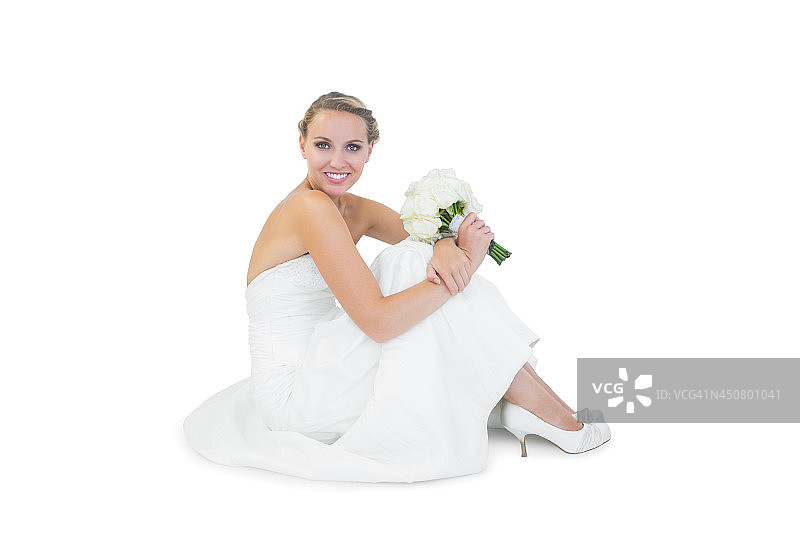 漂亮的金发新娘手捧花束坐在地板上图片素材