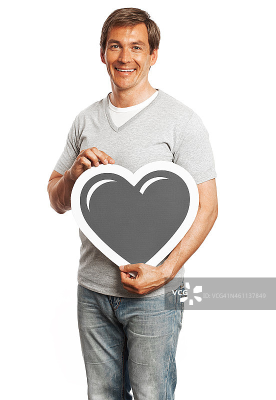 微笑的男人拿着心标志孤立在白色的背景。图片素材