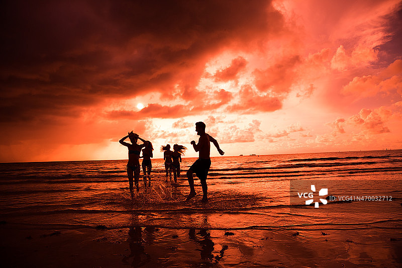 五个朋友在沙滩上欣赏美丽的红色日落图片素材