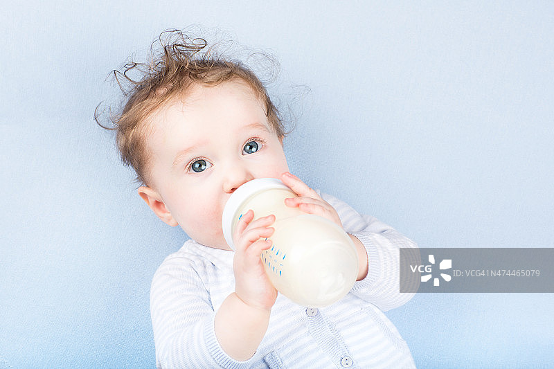 可爱的婴儿和奶瓶上的蓝色毯子图片素材