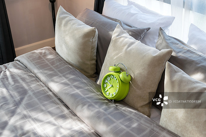 现代卧室，绿色闹钟和枕头在床上图片素材