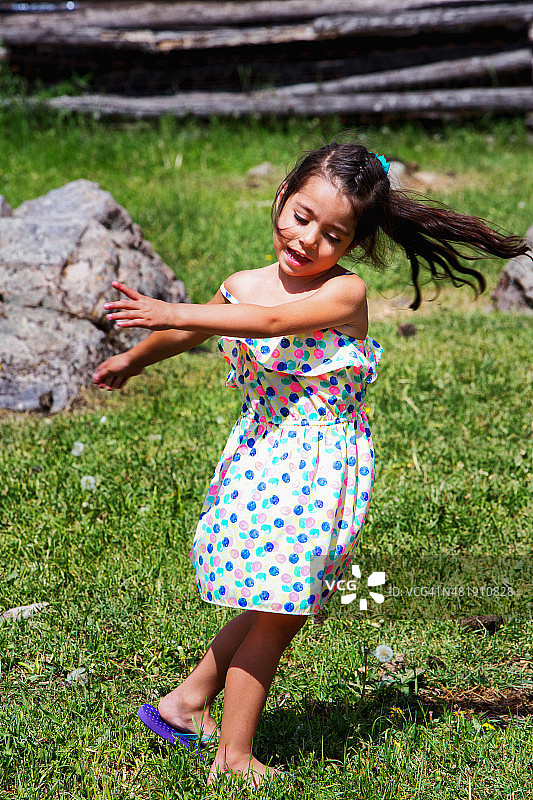 美丽的西班牙小女孩在外面的田野里旋转图片素材