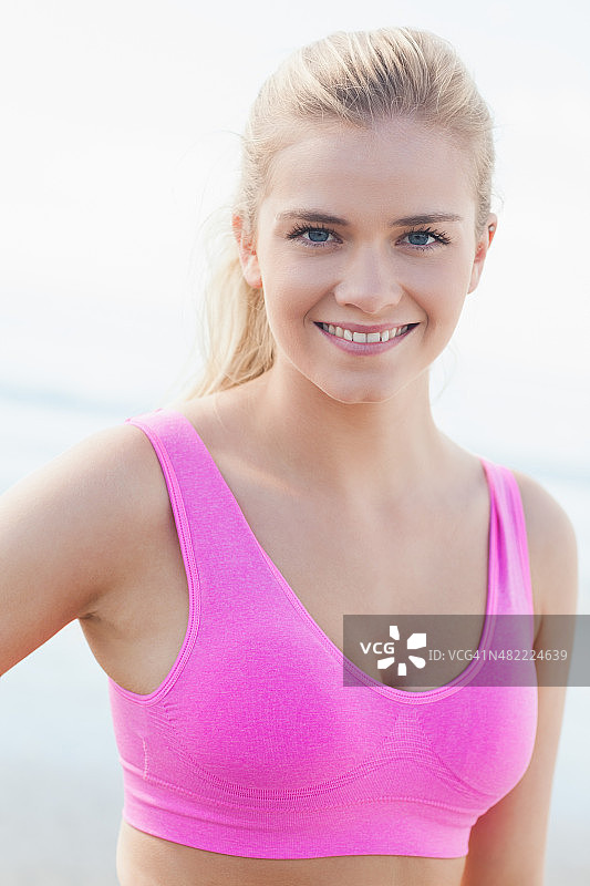 在海滩上穿着粉色运动胸罩微笑健康的女人图片素材