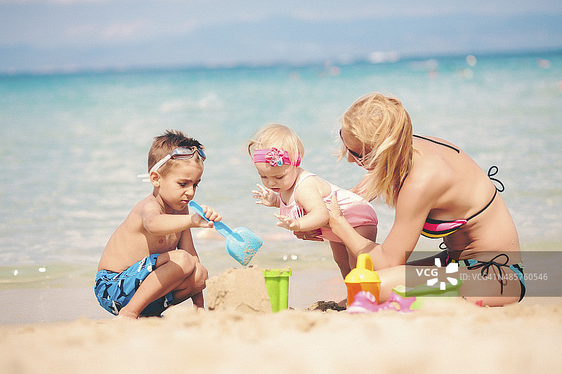 妈妈和孩子们在沙滩上玩沙子图片素材