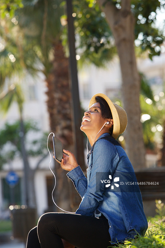 漂亮的年轻女子在手机上听音乐图片素材