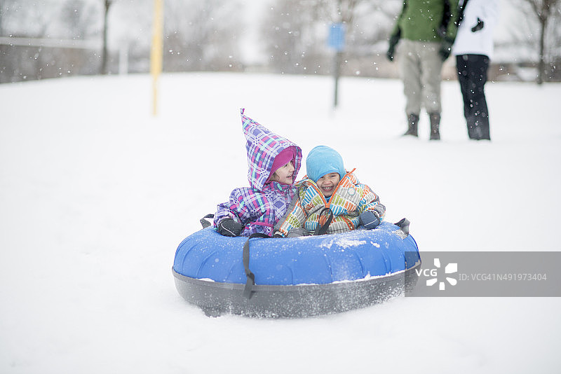 孩子们乘坐内胎下雪山图片素材