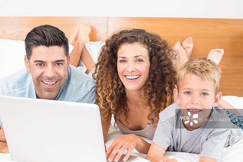 欢乐的一家人一起在床上使用笔记本电脑图片素材
