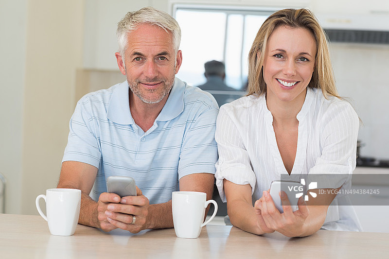 一对幸福的夫妇坐在柜台发短信图片素材