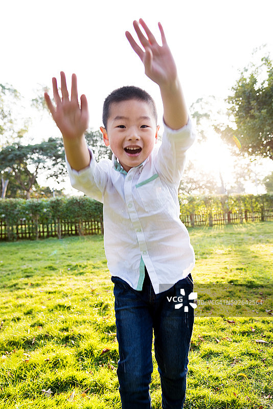 快乐的男孩在公园里蹦蹦跳跳图片素材