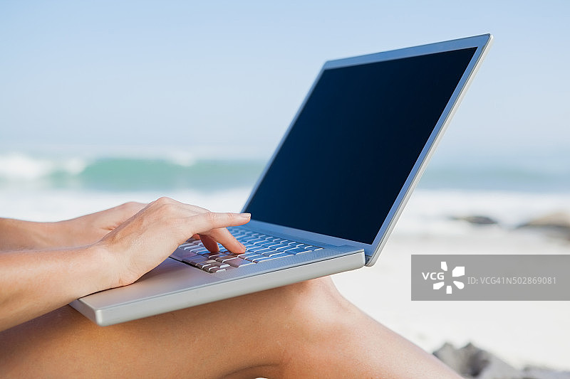 坐在沙滩上用笔记本电脑的女人图片素材