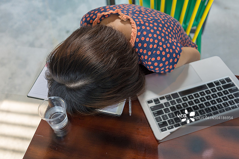 在笔记本电脑上工作后，沮丧的女商人睡在笔记本电脑上图片素材