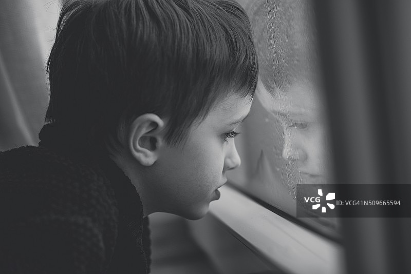 小男孩在窗边等待雨停- B&W图片素材