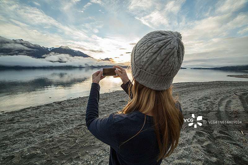 湖边的一名女子用手机捕捉风景图片素材
