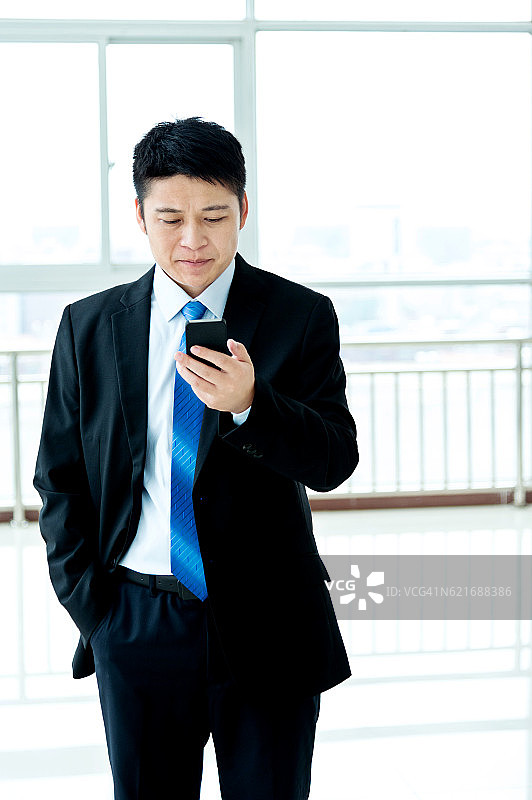 年轻的亚洲商人在办公室发短信图片素材