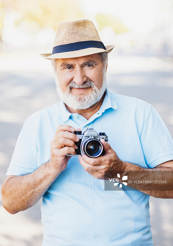 老人拿着相机。旅游的概念图片素材