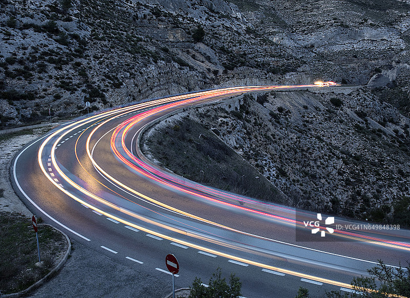 夜晚，车辆的灯光在蜿蜒的山路上循环图片素材
