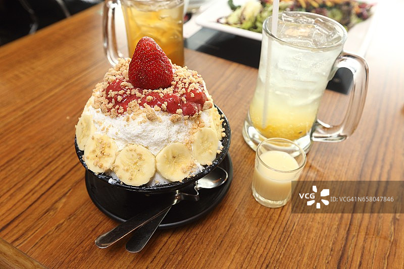 韩国甜冰甜点，著名的水果五颜六色的顶部和牛奶酱在木桌上图片素材