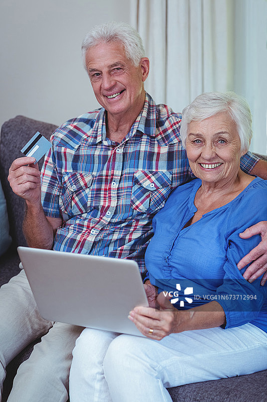 带着信用卡和笔记本电脑微笑的老年夫妇图片素材