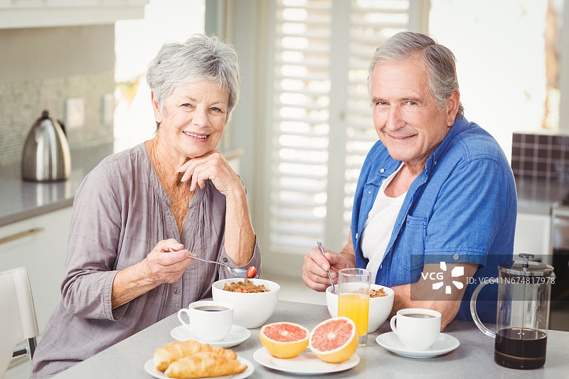 微笑的老年夫妇吃早餐的肖像图片素材