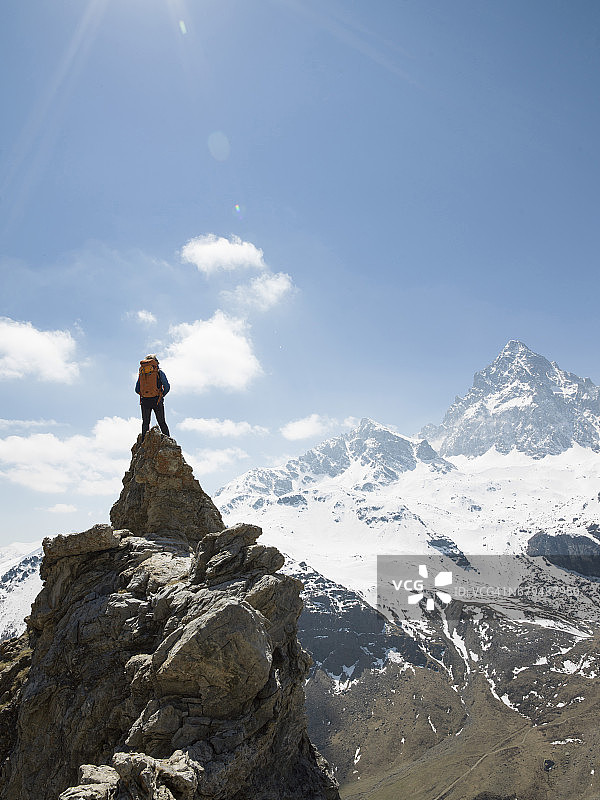 一名男性登山运动员站在山巅，俯瞰山谷图片素材