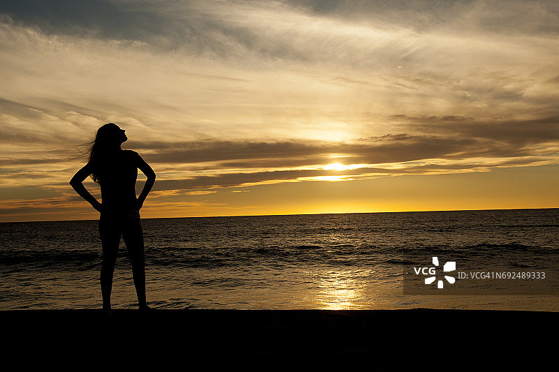 日落时分沙滩上的少女。图片素材
