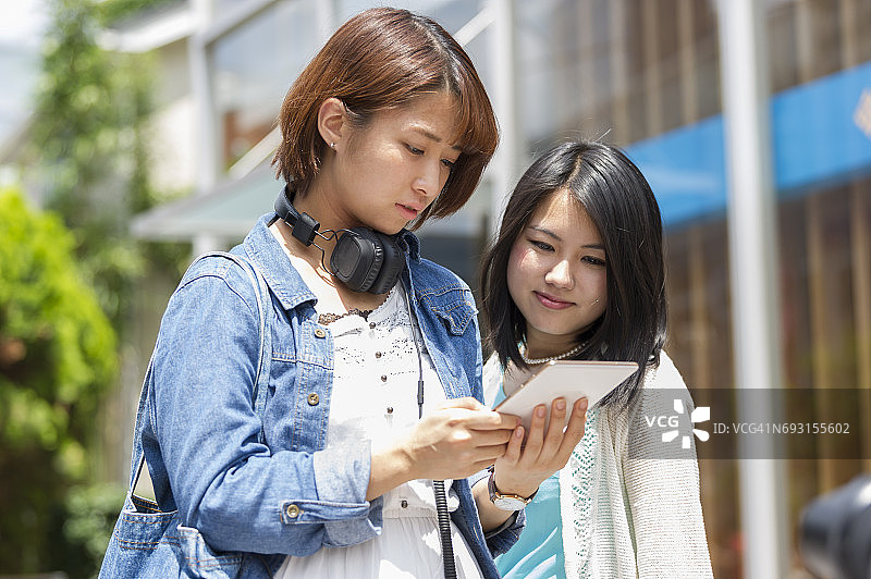 日本年轻女性在街上用平板电脑搜索图片素材