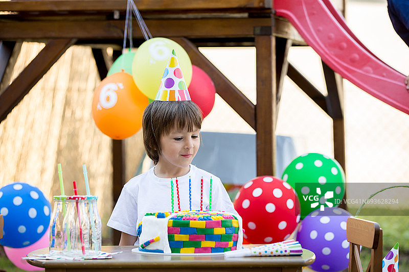 可爱的小男孩，庆祝他的六岁生日，蛋糕，气球，蜡烛，饼干。童年幸福的概念图片素材