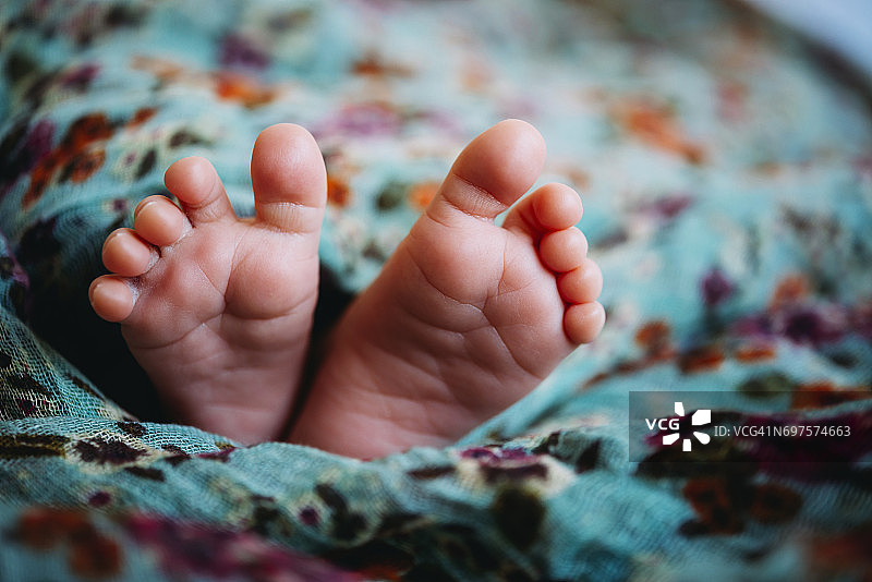 婴儿的脚躺在花毯子下面图片素材
