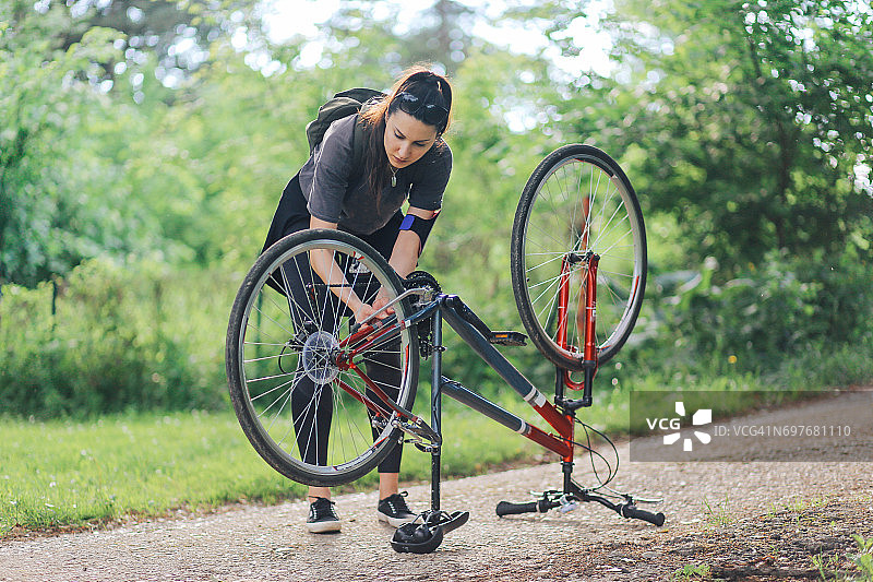 年轻女子正在修理她的自行车图片素材