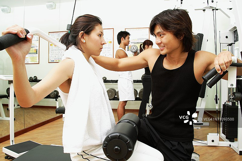 在健身房锻炼的夫妇，举重训练，背景中的人图片素材