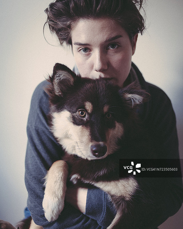 灰色背景下的自信女人拥抱狗的肖像图片素材