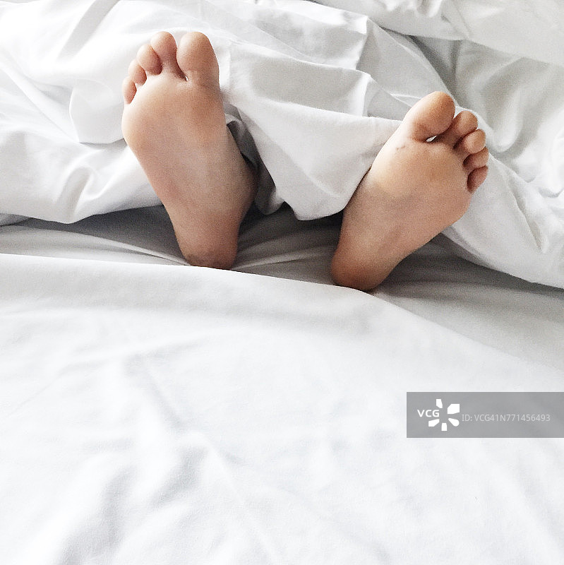 一个男孩的脚躺在床上的特写图片素材