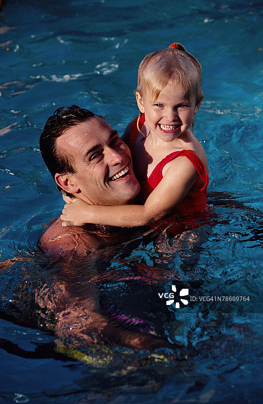 父亲和女儿一起在游泳池里图片素材