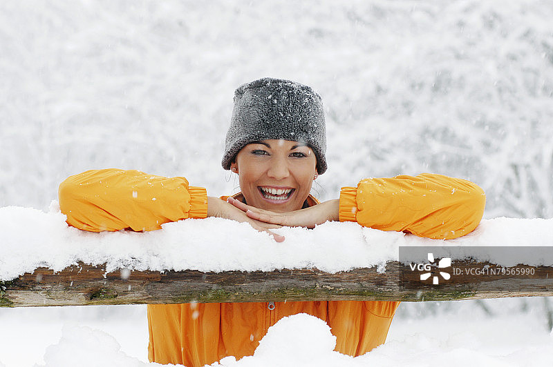 年轻女子在雪地里倚在木栏杆上图片素材