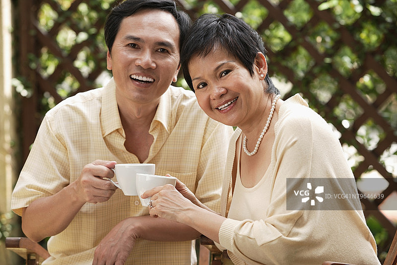 成熟的夫妇在喝茶时对着镜头微笑图片素材