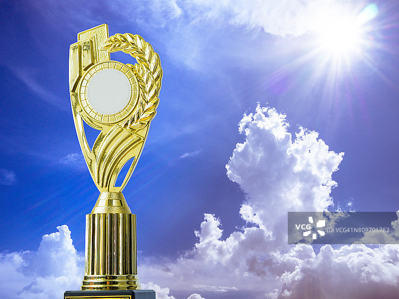 金奖获奖奖杯在蓝天和太阳的背景图片素材