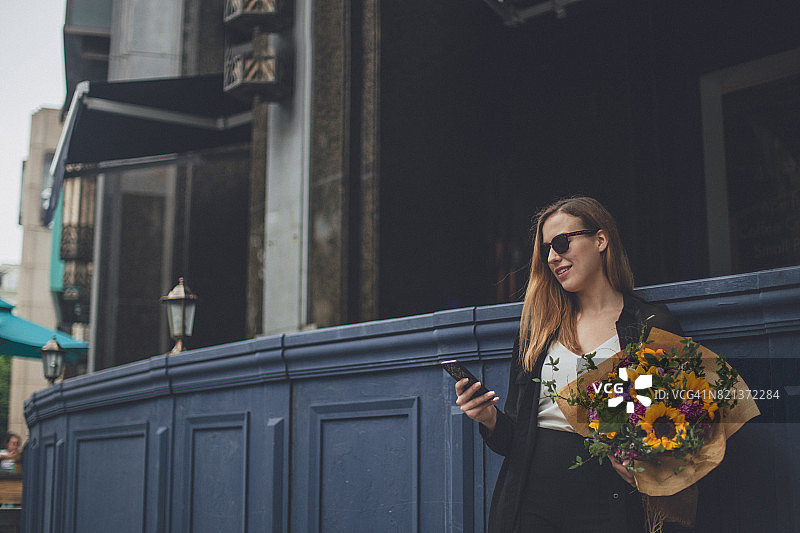 一个女人站在外面，手里拿着一束花图片素材