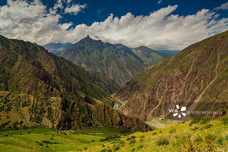 从隘口到绿色山谷和山脉的景色。吉尔吉斯斯坦图片素材