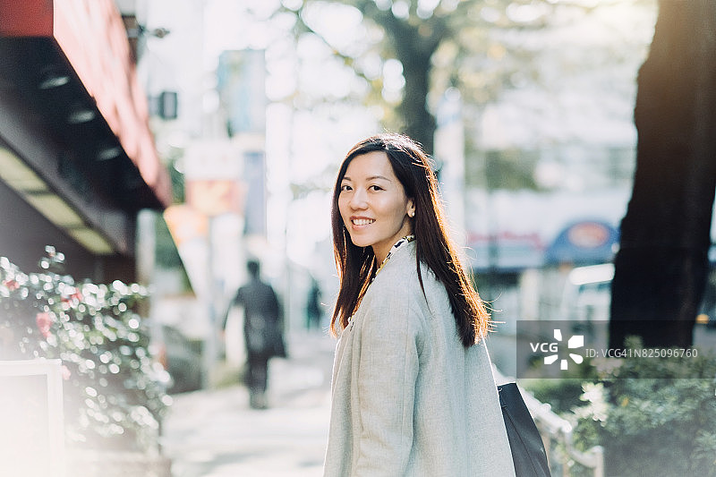 美丽的亚洲女人回头微笑在街上图片素材