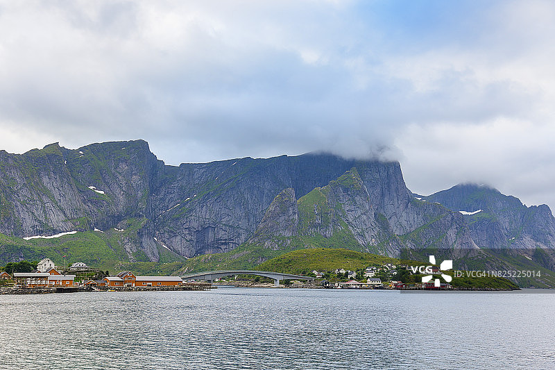 挪威的一个渔村，位于挪威罗浮敦群岛。壮观的晚霞在陡峭的山峰上移动。图片素材