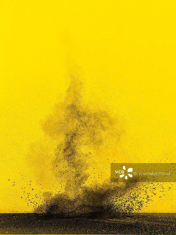由灰色、黑色和黄色背景组成的粉末云的爆炸图片素材
