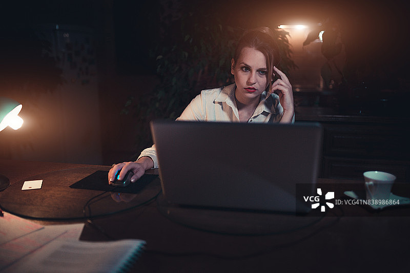 疲惫的女人在黑暗中沉思，用笔记本电脑工作图片素材