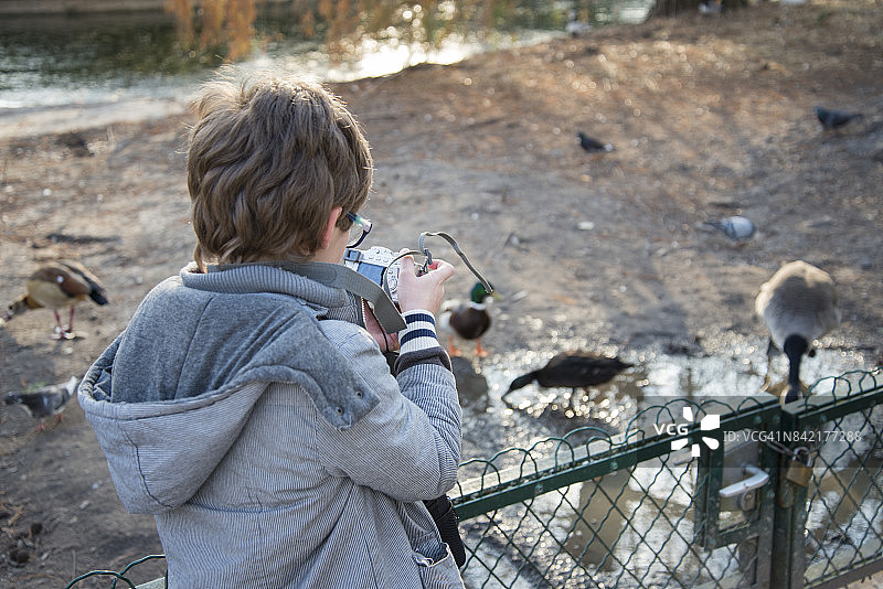 一个孩子在公园里用数码相机拍鸟图片素材