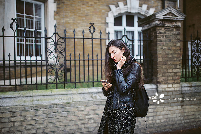 一名年轻女子在伦敦街头边走边发短信图片素材