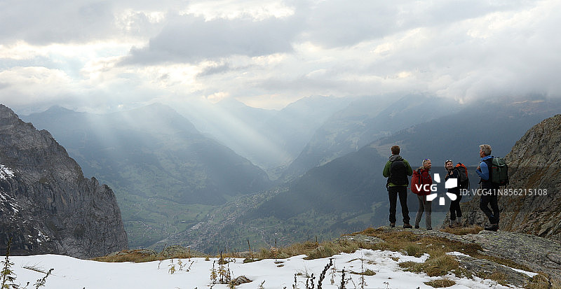 家庭的徒步旅行者探索积雪的山脊之上的山谷，山脉图片素材